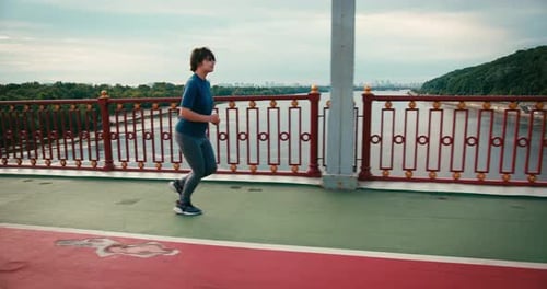 Woman Running on Bridge in Urban Setting