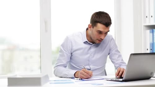 Man Working at Desk with Laptop and Documents