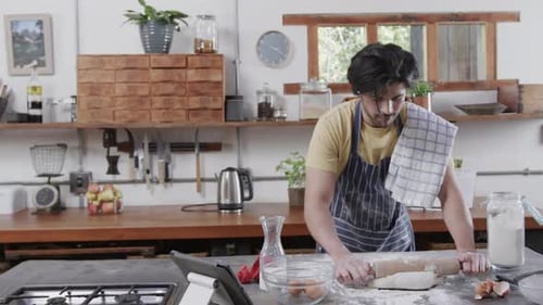 Caucasian man preparing bread dough using tablet in kitchen, slow motion