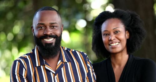 Two African couple smiling at camera outside at park