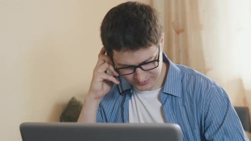 Young Adult Using Laptop Then Answers Phone