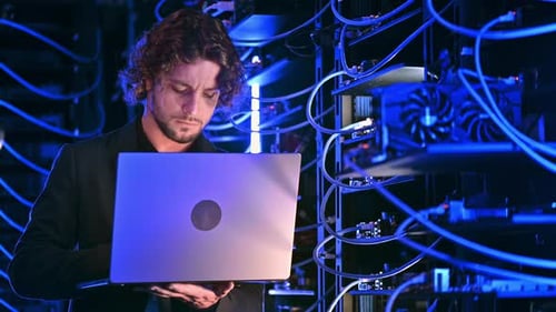 Man Using Laptop in Dark Server Room