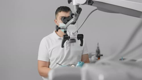 Dentist Using Microscope on Patient in Clinic