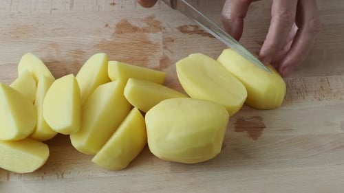 Hands Cutting Potatoes on a Wooden Cutting Board