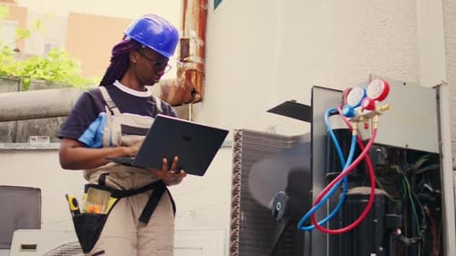 HVAC Technician Using Laptop for Equipment Maintenance
