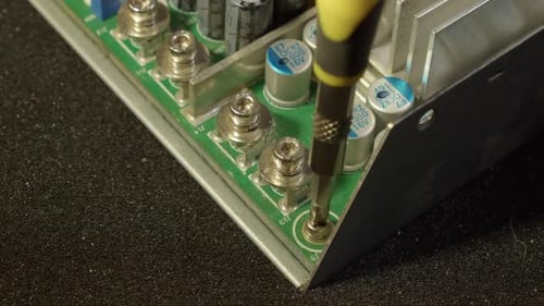 Circuit board of capacitors is unscrewed from electronics chassis