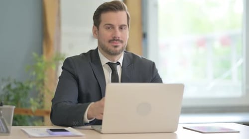 Businessman Gives Thumbs Up at Office Desk