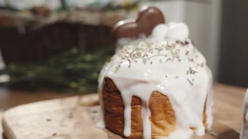 Hausgemachte Osterkuchen mit tropfender weißer Glasur auf einem Holztisch, beleuchtet vom Sonnenlicht