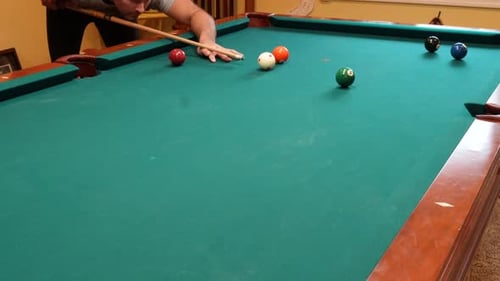 Man Playing 8 Ball Pool Shoots Several Solid Balls into Pockets on a Brunswick Table for Billiards w