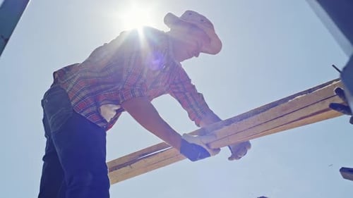 Man Working with Lumber in Bright Sunlight