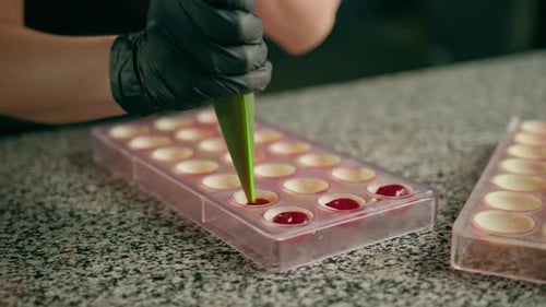 Pastry chef makes chocolates Tempering chocolate pours melted chocolate from a pastry sleeve into