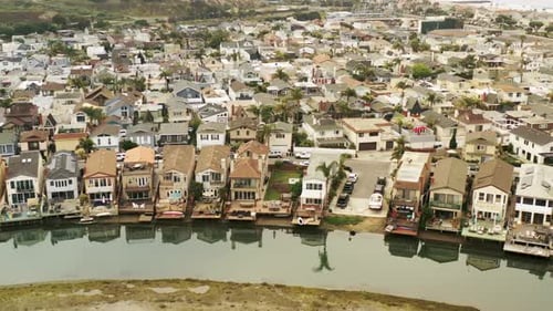 Aerial view of beachfront homes along a channel that rotates to reveal the ocean.