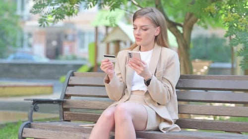 Woman Shopping Online with Credit Card on Park Bench