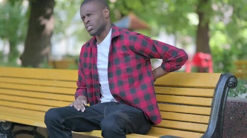 Man Suffering from Back Pain on Bench