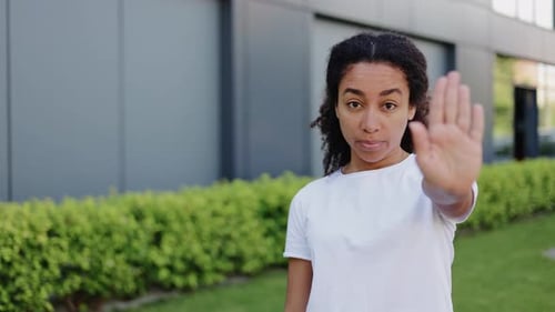 Woman Gestures Stop with Hand Outside Building