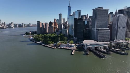 An aerial view of lower Manhattan and New York Harbor on a sunny day with blue skies. The drone came