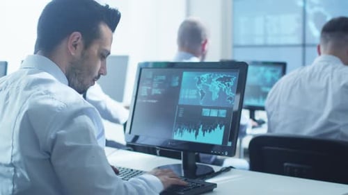 Une équipe de professionnels de la sécurité informatique travaille dans une salle de surveillance lumineuse remplie d'écrans