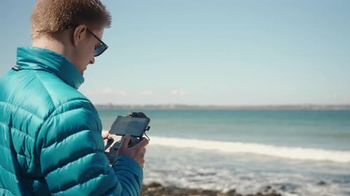 Young Adult Controls Drone on Beach