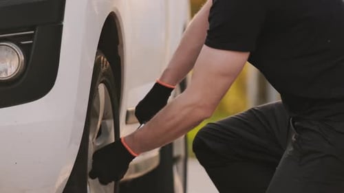 Man Changing Tire on White Van During the Day
