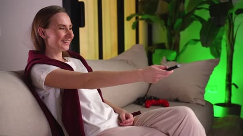 Woman Laughing and Watching TV on Sofa