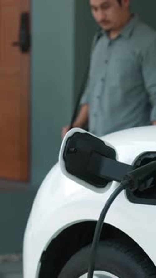 Progressive man unplugs the electric vehicle's charger at his residence.