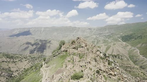Ancient Mountain Village Overlooking Green Valley Under Cloudy Sky