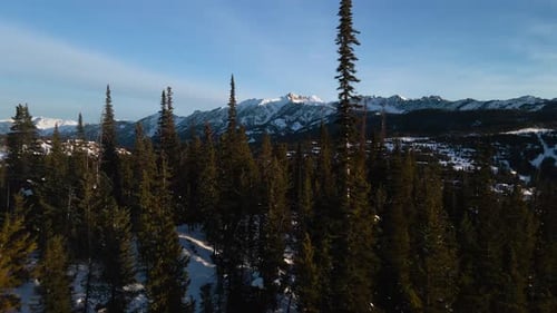 A drone shot of snowy Big Sky, Montana in winter, showcasing the ski resort and majestic mountain te