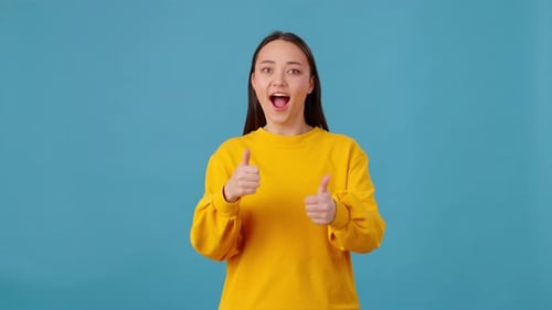 Excited Female Making Thumb Up Gesture on Blue Background