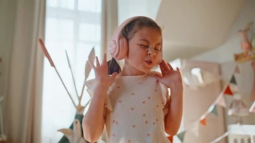 Energetic Girl with Headphones Dancing and Singing Indoors
