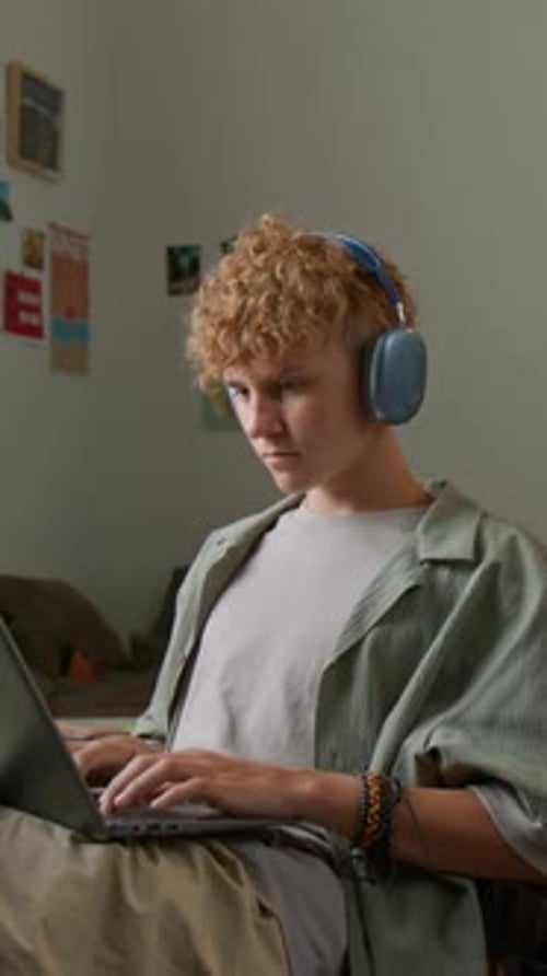 Man with Headphones Using Laptop Indoors at Home
