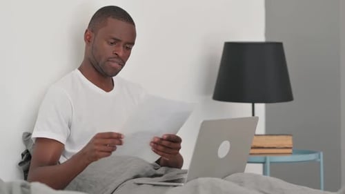 Young Adult Working in Bed with Laptop