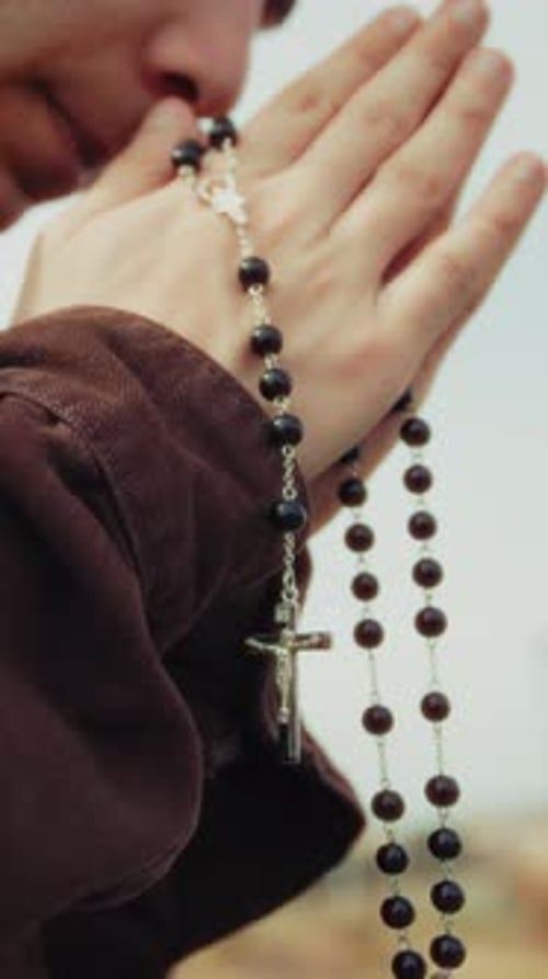 Young Man Praying with Rosary Beads, Close Up