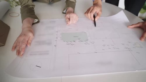 Two adults reviewing architectural plans at a table