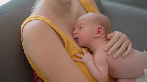 A Young Mother Lovingly Cradles Her Tiny Newborn Baby in Her Arms Sharing a Heartwarming Moment of