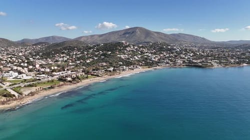 Scenic aerial shot of a peaceful seaside town with clear sea, beach, and coastal houses.