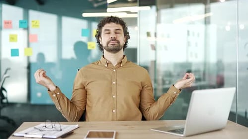Calm Man Meditating at Desk in Modern Office