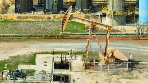 Drohnen-Luftaufnahme eines Pumpjackers, der an einer Ölförderstelle arbeitet.