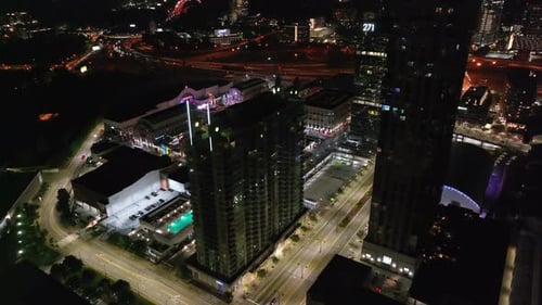 Fly above modern urban borough in metropolis. Aerial night shot of modern high rise buildings and he