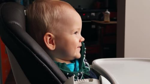 Adorable Infant Eats Food in High Chair