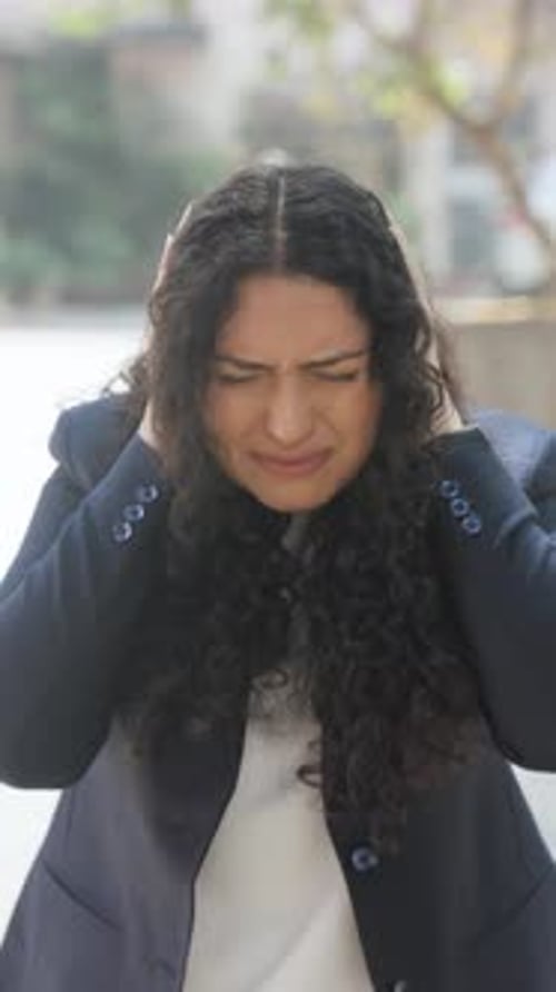 Woman Holding Head in Distress Outdoors