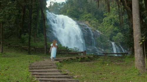 Woman Walking to Waterfall in Lush Tropical Forest