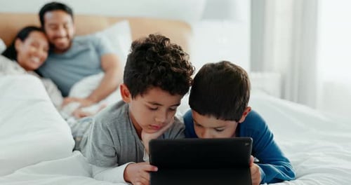 Children Using Tablet with Parents in Background