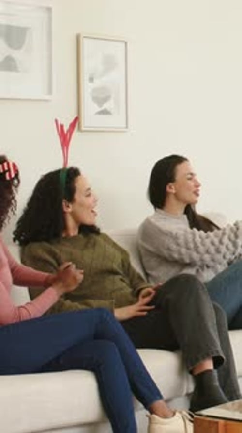 Vídeo vertical: Alcançando uma mulher de suéter verde aceitando presente embrulhado após presente estendido no sofá