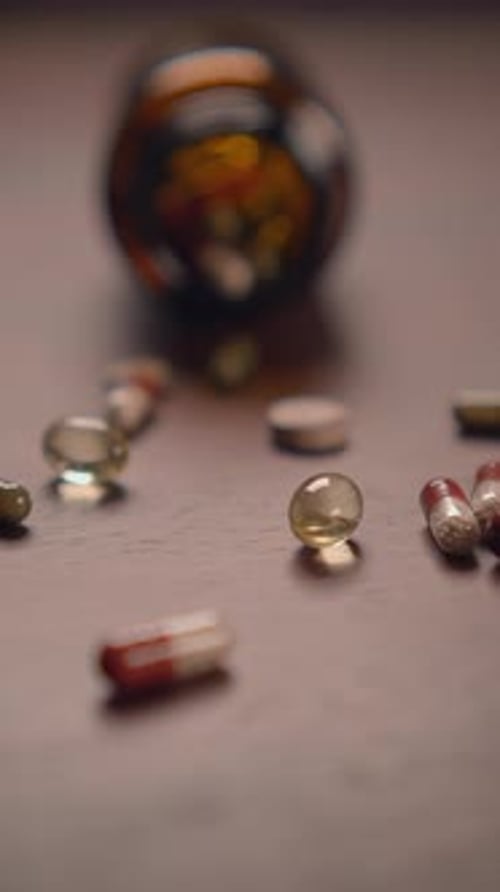 Pills and Capsules Spilled from Glass Bottle