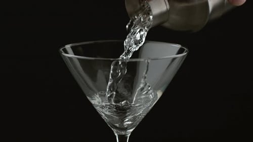 Pouring clear liquid into a martini glass