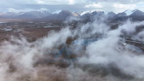Aerial view of road and lakes through thick clouds