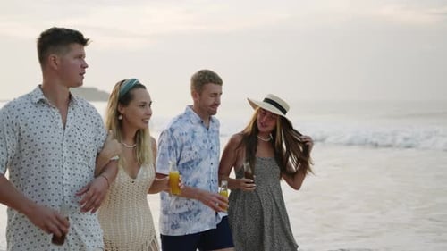 Groupe d'amis d'hommes et de femmes avec des bouteilles de kombucha marchent sur une plage tropicale ensoleillée Drink Talk Smile Two