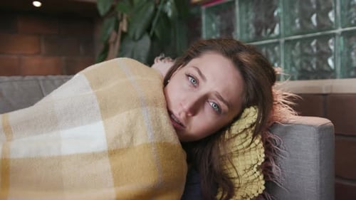 Close Up Face Woman Has a Fever Cold Lying on Sofa Look at Camera Headache Feel Sick at Home Virus