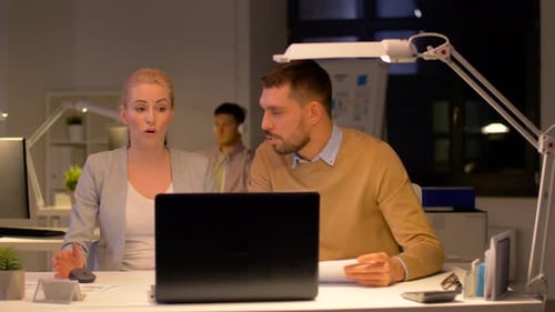 Frustrated business team works late on laptop in modern office under deadline pressure