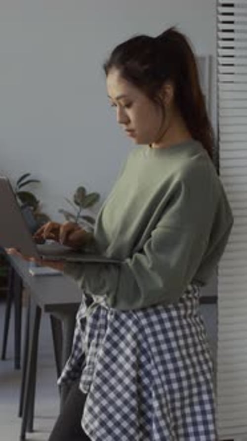 Young Asian Woman Working on Laptop while Standing in IT Company Office